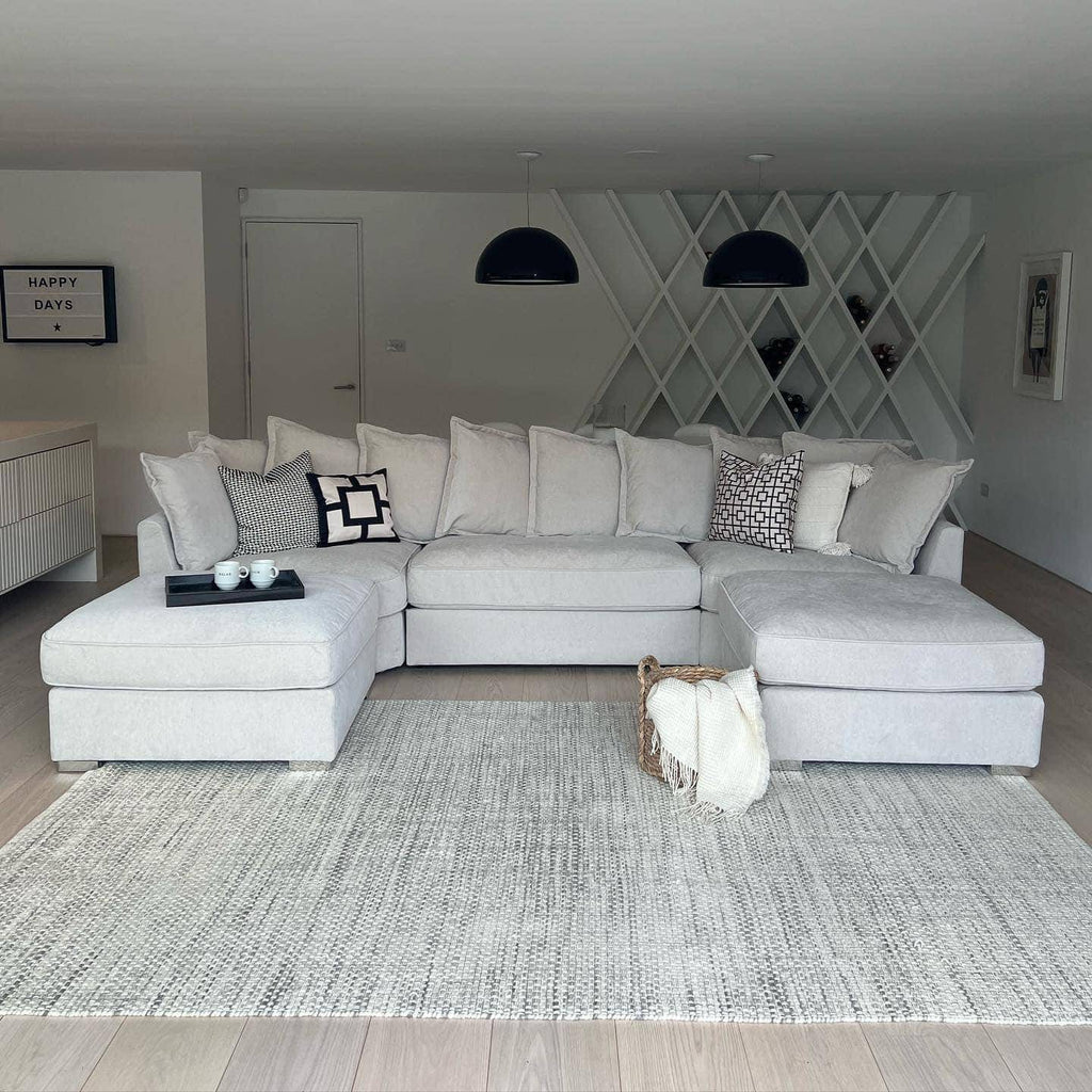 Modern living room with a large U-shaped light grey sofa and neutral decor accents