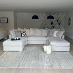 Modern living room with a large U-shaped light grey sofa and neutral decor accents