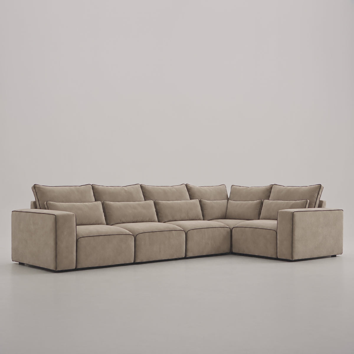 Maison 5 Piece Modular Single Corner Sofa in a minimal studio with an adult model demonstrating scale