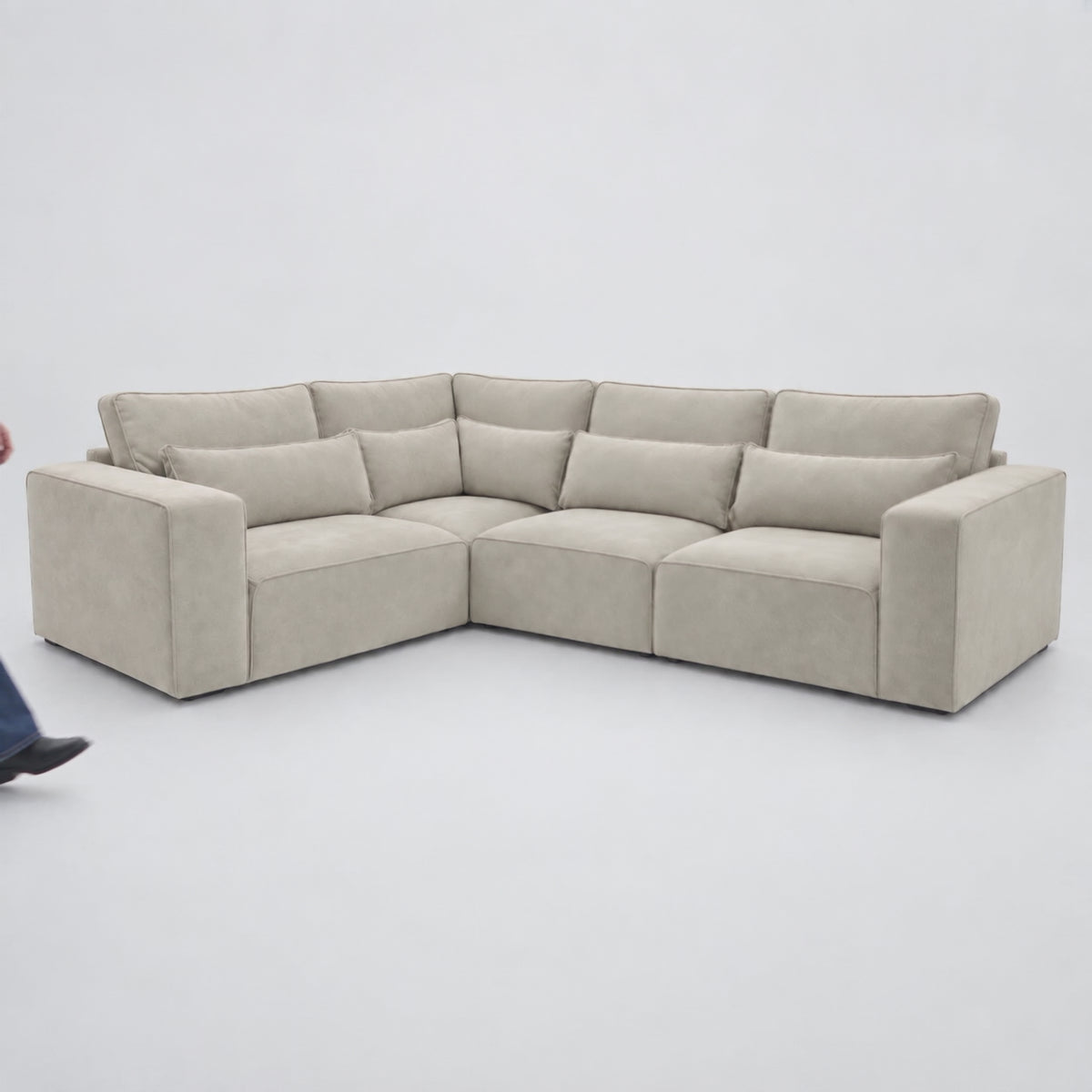 Maison 4 Piece Modular Corner Sofa - Single Corner in a minimal studio with an adult model demonstrating scale