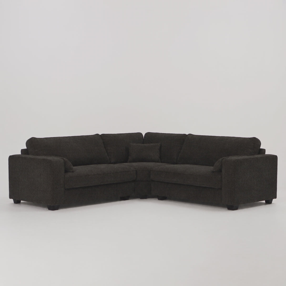 Verdi Corner Sofa in black — frontal studio scale demonstration with model walking left to right