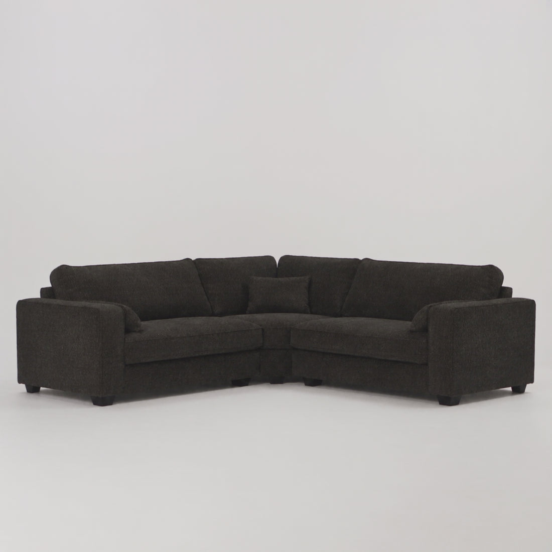 Verdi Corner Sofa in black — frontal studio scale demonstration with model walking left to right