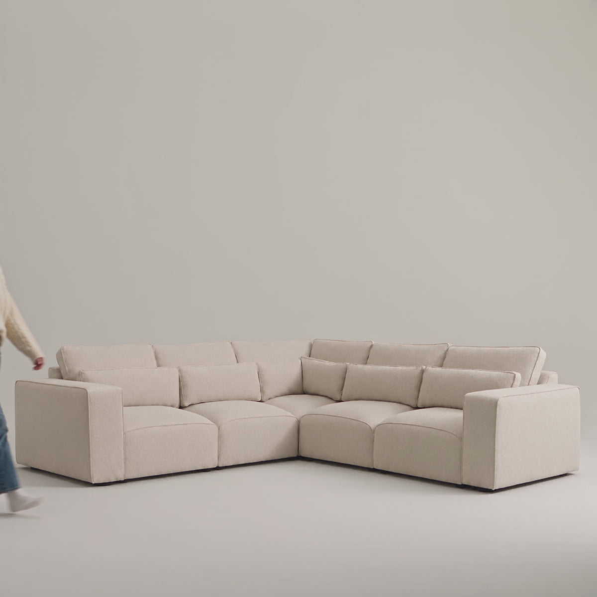 Maison 5 Piece Double Corner Sofa in a minimal studio with an adult model demonstrating scale