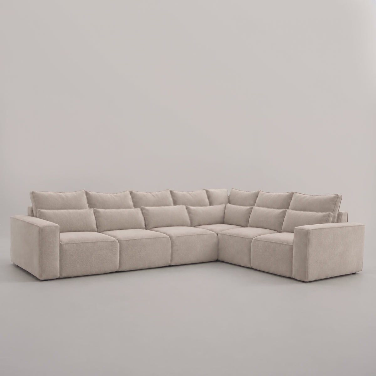 Maison 6 Piece XL Modular Corner Sofa - Closed End in a minimal studio with an adult model demonstrating scale