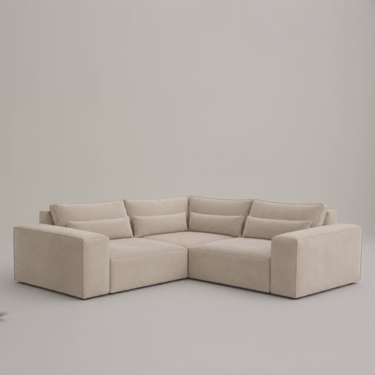 Maison Modular Small Double Corner Sofa in a minimal studio with an adult model demonstrating scale