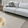 Modern white sofa with green leaf pillow on textured rug in living room