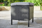 Grey wicker outdoor ottoman with cushion on patio, perfect for garden seating