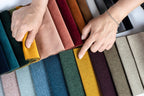 Hands selecting colourful upholstery fabric swatches for sofas or beds