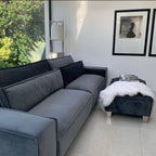 Modern grey 4-seater sofa with matching footstool in a bright living room with wall art.