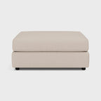 Modern beige upholstered footstool with clean lines on a plain background