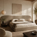 Luxury upholstered bed with curved headboard in neutral tones, styled with linen bedding and modern bedside lamps