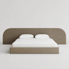 Modern upholstered bed with curved headboard, white linens, luxury bedroom furniture