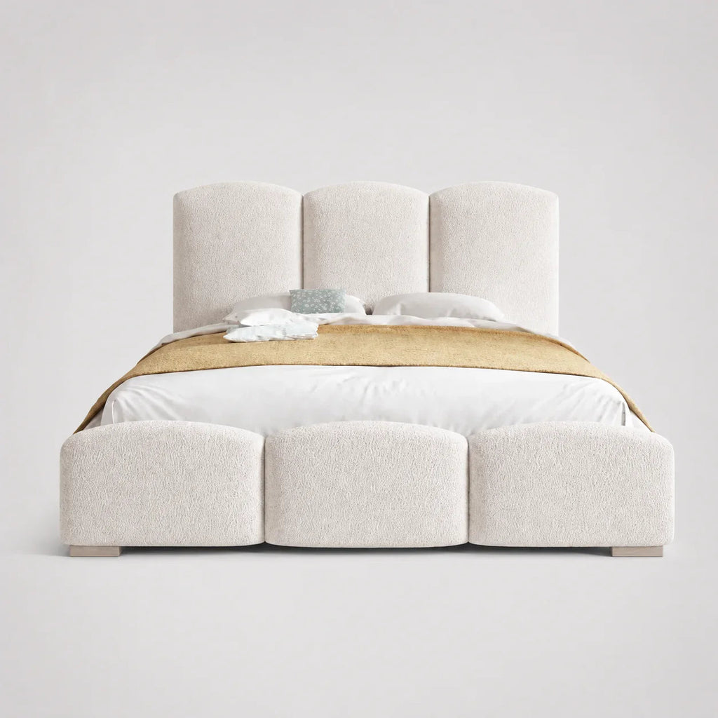 Luxury upholstered bed with segmented headboard and footboard, white bedding, gold throw