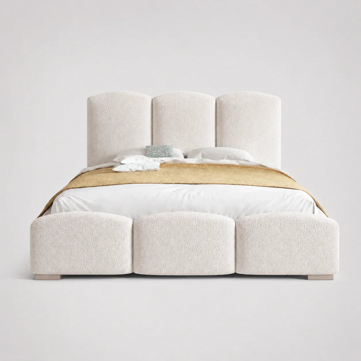 Luxury upholstered bed with segmented headboard and footboard, white bedding, gold throw