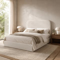 Luxury upholstered bed with neutral bedding, modern bedside tables, and natural light in a serene bedroom