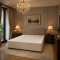 Luxury upholstered bed frame in elegant bedroom with chandelier and dark wood nightstands